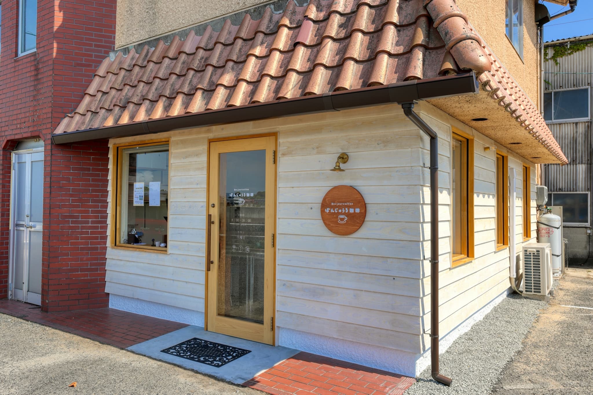 赤茶色の瓦屋根と白い板張りの壁のぼんじゅうる珈琲の建物全景